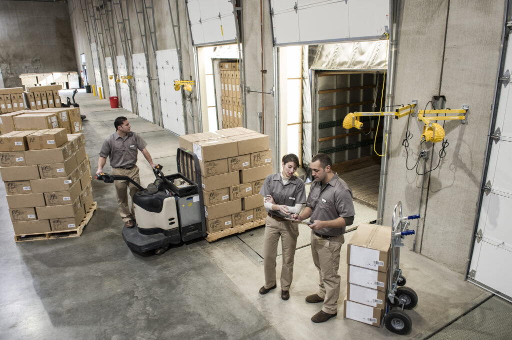 Uniformed warehouse workers loading boxed optimising trailer loads in warehouse.