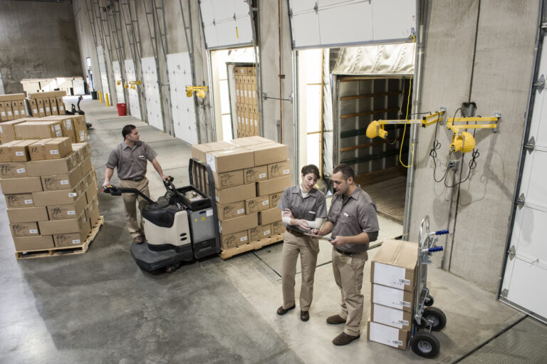 Uniformed warehouse workers loading boxed optimising trailer loads in warehouse.